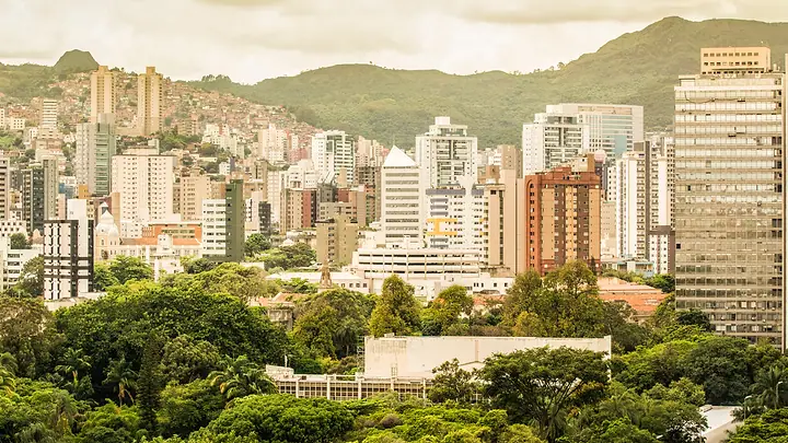 Prédios de Belo Horizonte entre árvores, com a serra ao fundo